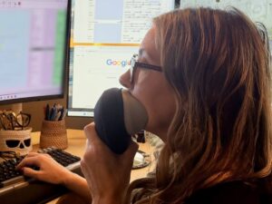 Close-up of a court reporter speaking into a stenomask while typing at a computer