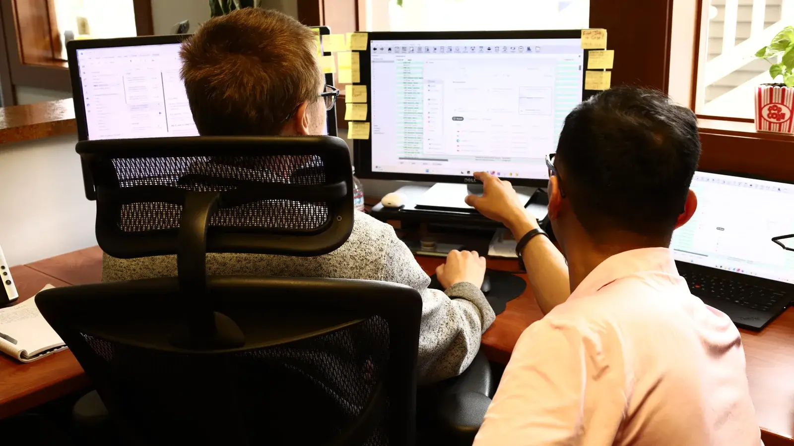 Two B&A staff members working together at their monitors