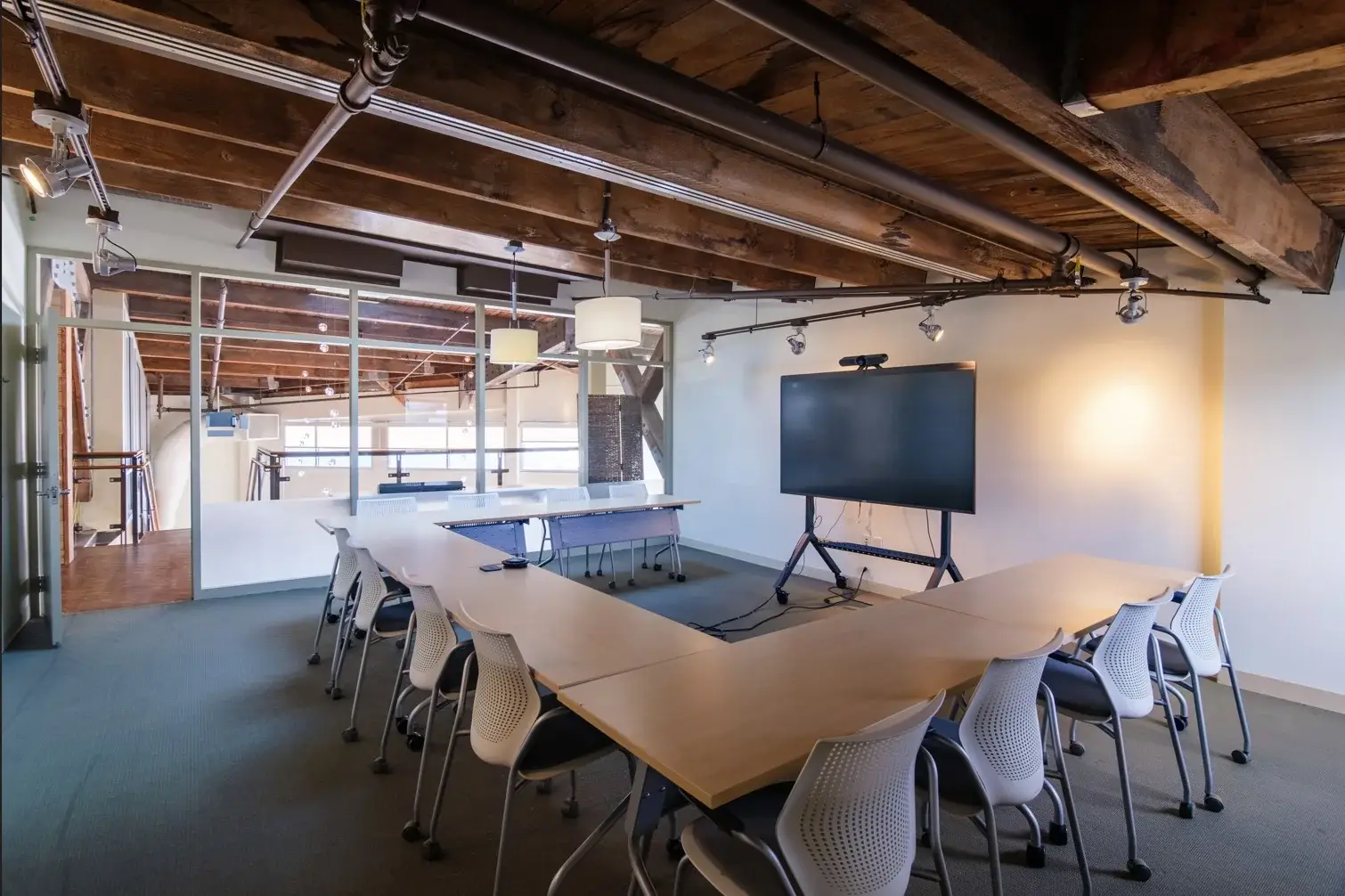 Large conference room at B&A’s Seattle office, with U-shaped tables and a display with a conference camera for hybrid depositions