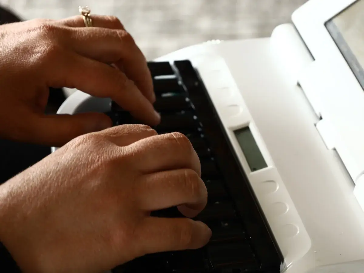 A court reporter's hands writing on a stenotype machine